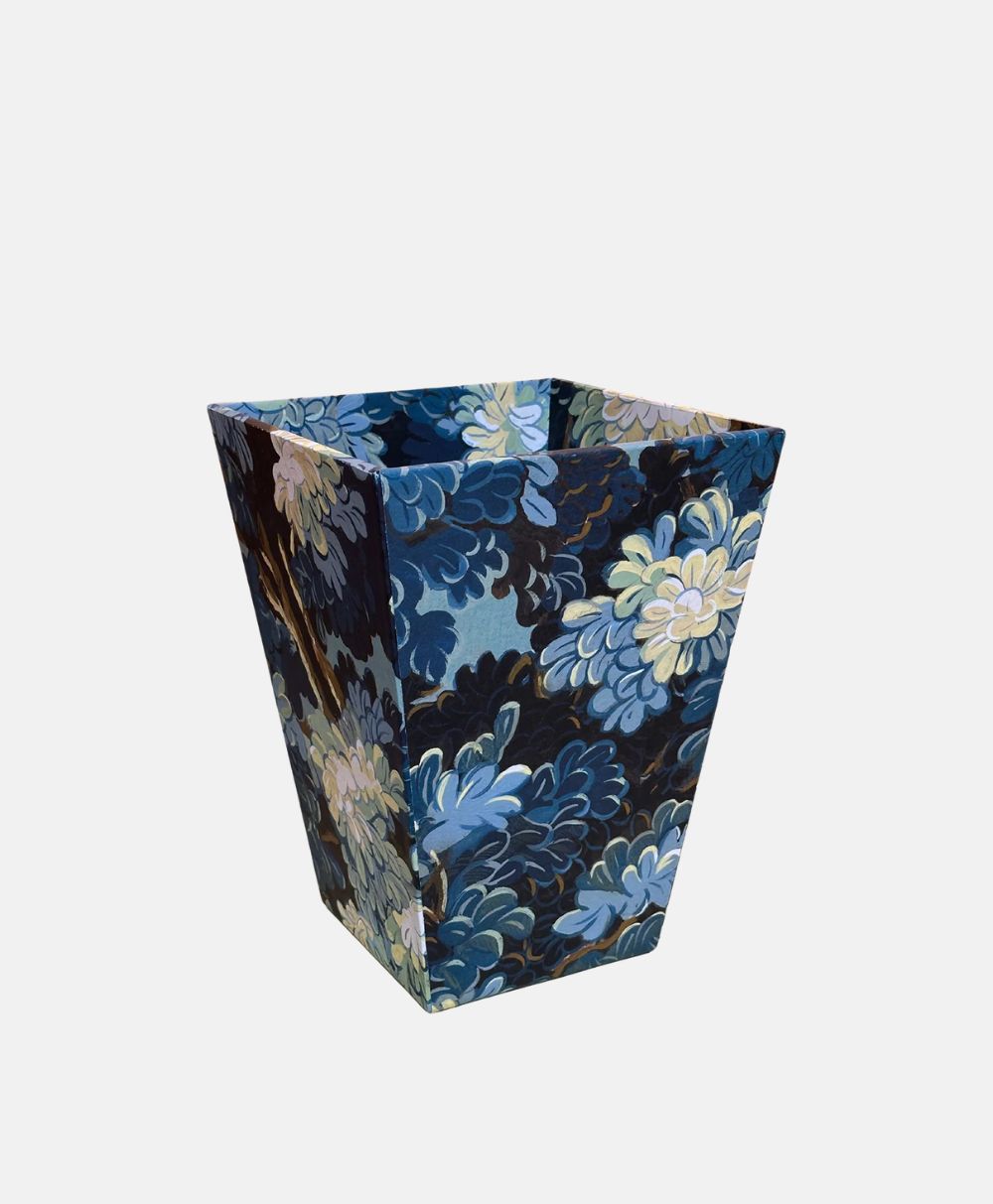 A rectangular waste bin with a flared top, featuring a dark blue, light blue, and white floral pattern on all sides, set against a plain light gray background.