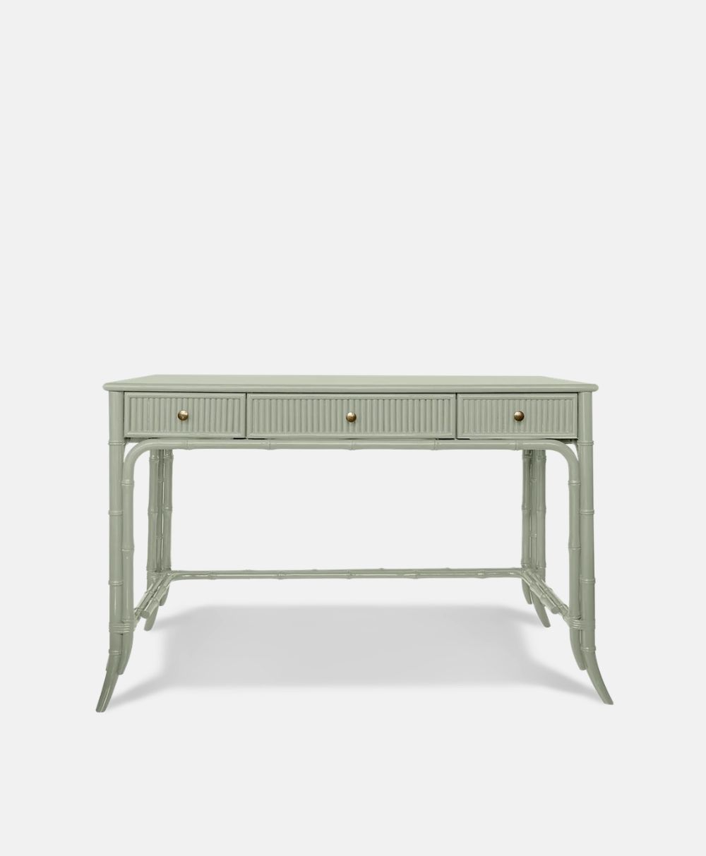A light green writing desk with three drawers, brass knobs, and faux bamboo-style legs, set against a plain white background.