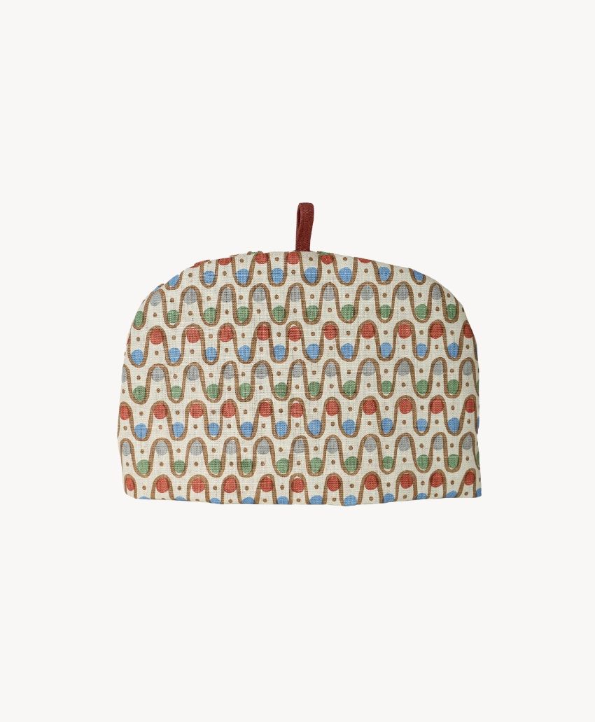 Cathy Nordström Iteru Desher Red tea cosy with a wavy red, blue and green pattern on cream and a brown loop handle